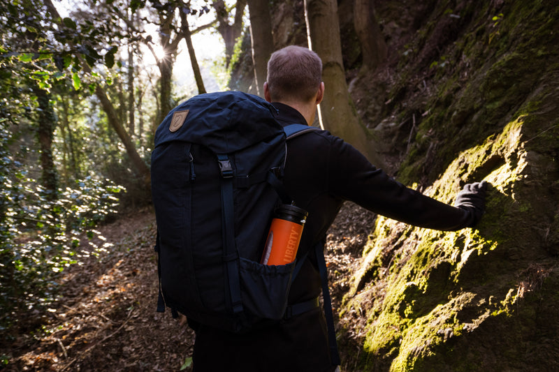 Laden Sie das Bild in Galerie -Viewer, Hiker climbing a steep forest path with an orange LifeSaver Liberty in his backpack